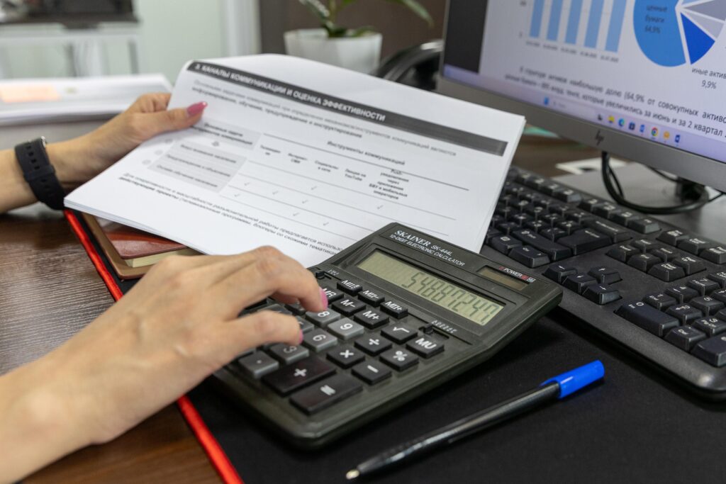 pexels-photo-33175649-33175649 A person calculates financial data using a calculator and document, working at an office desk.